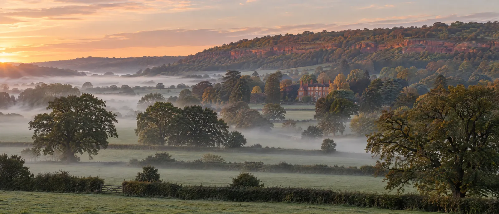 Mist over Cheshire fields at dawn, with the sandstone ridge beyond